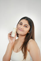 Woman holding a skincare product against a plain background
