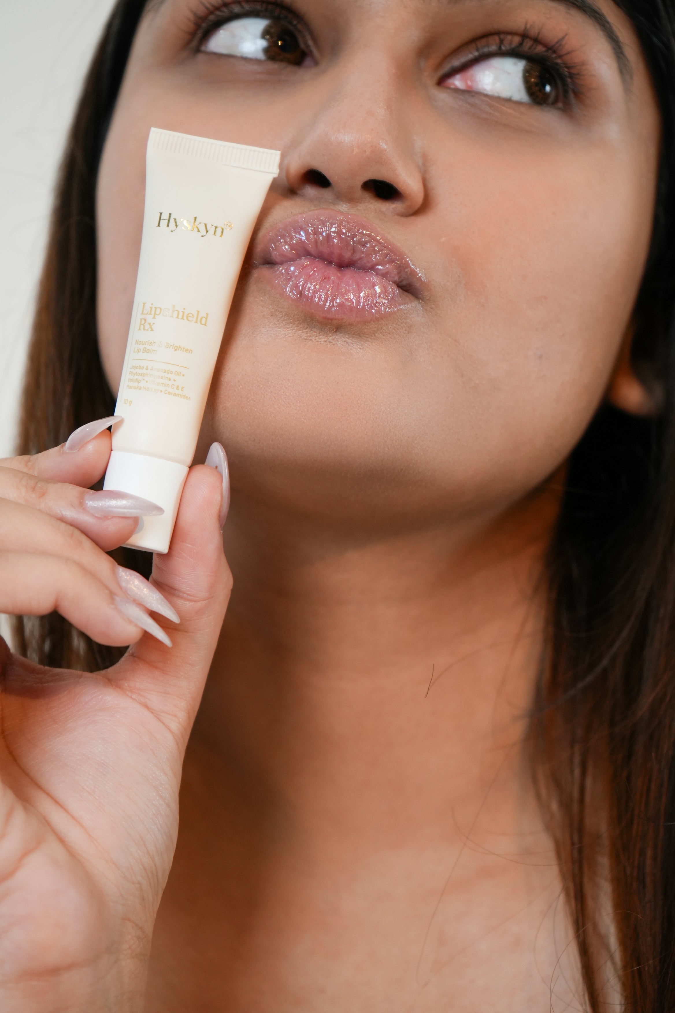 Woman holding a tube of hydrating lip balm close to her lips
