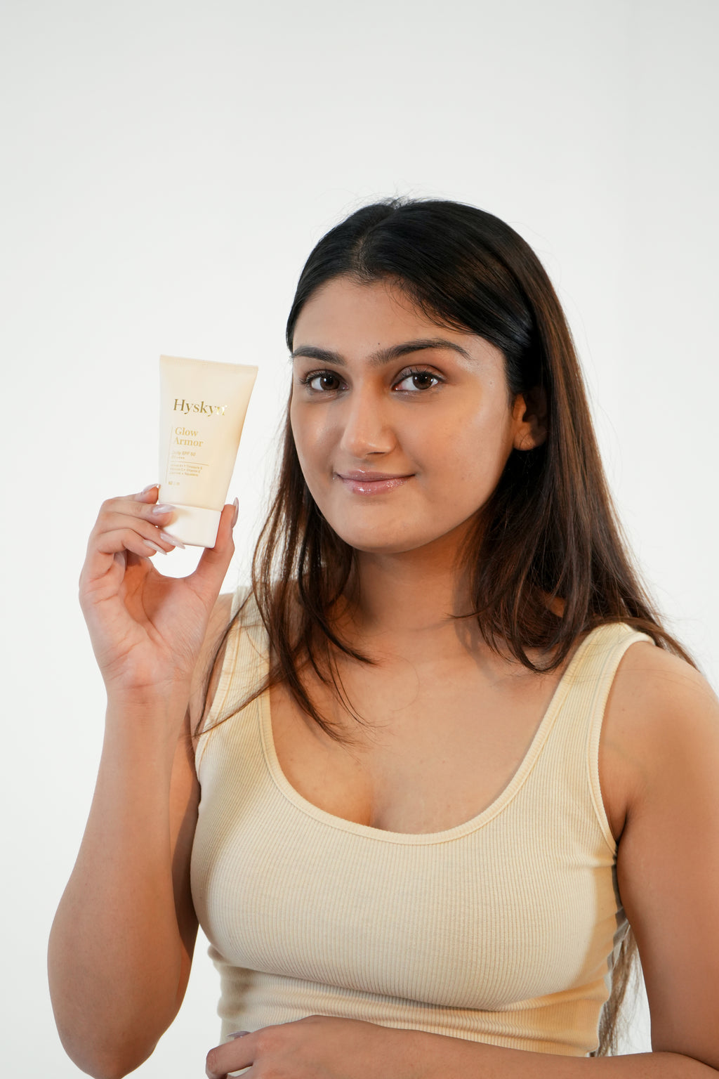 Woman holding a broad spectrum sunscreen product against a white background